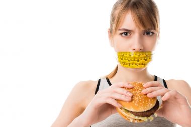 ağzı olan genç kadın üzerinde beyaz izole burger tutan teyp ölçme bağlı