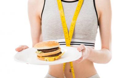 Teyp üzerinde beyaz izole hamburger ile plakası tutan ölçme ile ince kadın kırpılmış atış