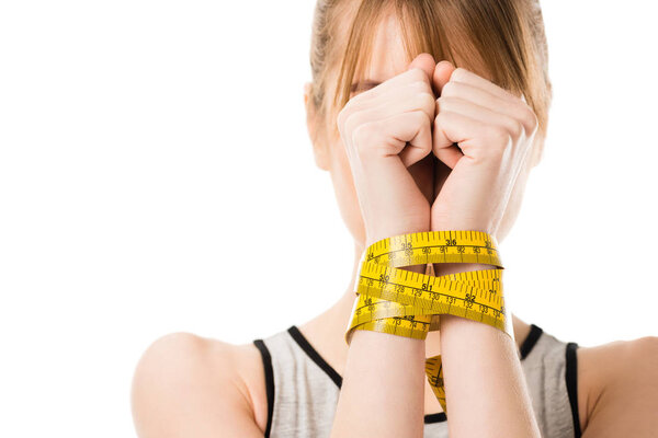 женщина покрывает лицо руками, привязанными к измерительной ленте, изолированной на белом
