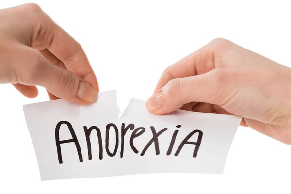 cropped shot of woman tearing paper with anorexia inscription isolated on white