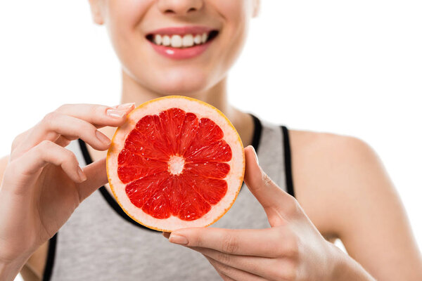 cropped shot of young smiling woman with half of grapefruit isolated on white