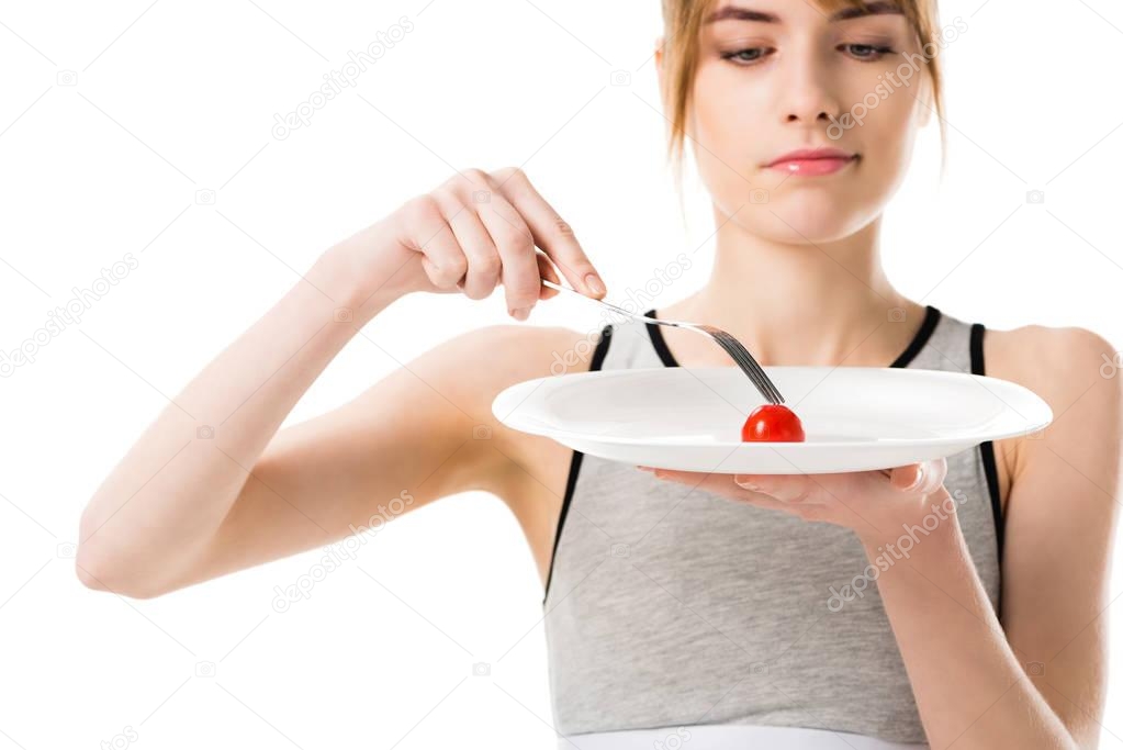 attractive slim woman eating tiny cherry tomato isolated on white