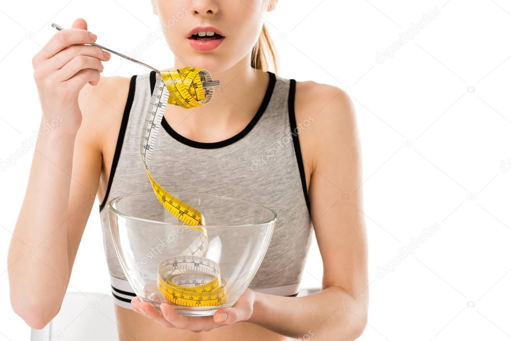 cropped shot of young woman eating mesuring tape isolated on white, anorexia concept