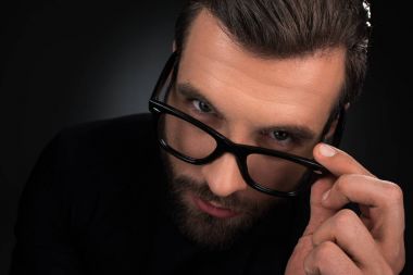portrait of man in eyeglasses looking at camera isolated on black clipart