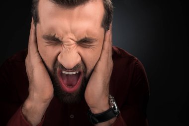 portrait of screaming man covering ears isolated on black clipart