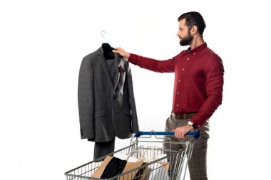 man with shopping cart full of shopping bags looking at jacket in hand isolated on white clipart