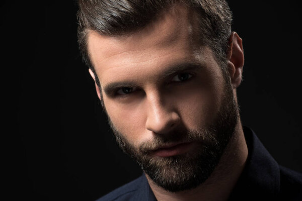 portrait of confident bearded man looking at camera isolated on black