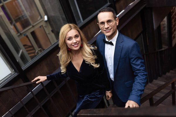 high angle view of adult couple in stylish clothing going up stairs
