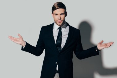 Omuz silkme hareketi beyaz arka plan üzerinde gösterilen takım elbiseli genç işadamı