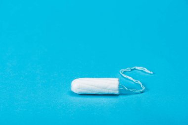 one menstrual tampon isolated on blue clipart