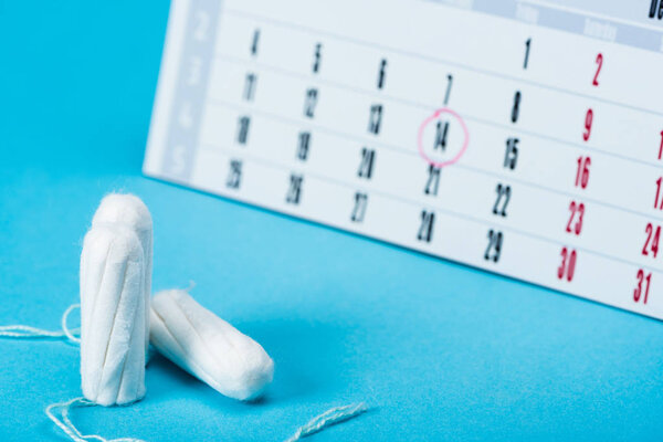 three menstrual tampons and calendar on blue