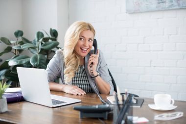 smiling businesswoman talking by telephone in office