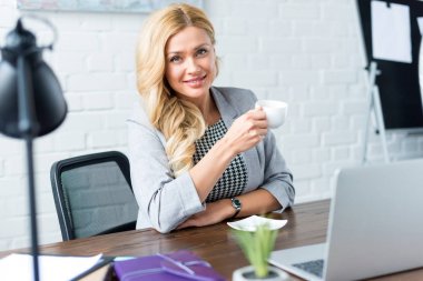 işkadını holding fincan kahve ofis ve kameraya bakarak gülen