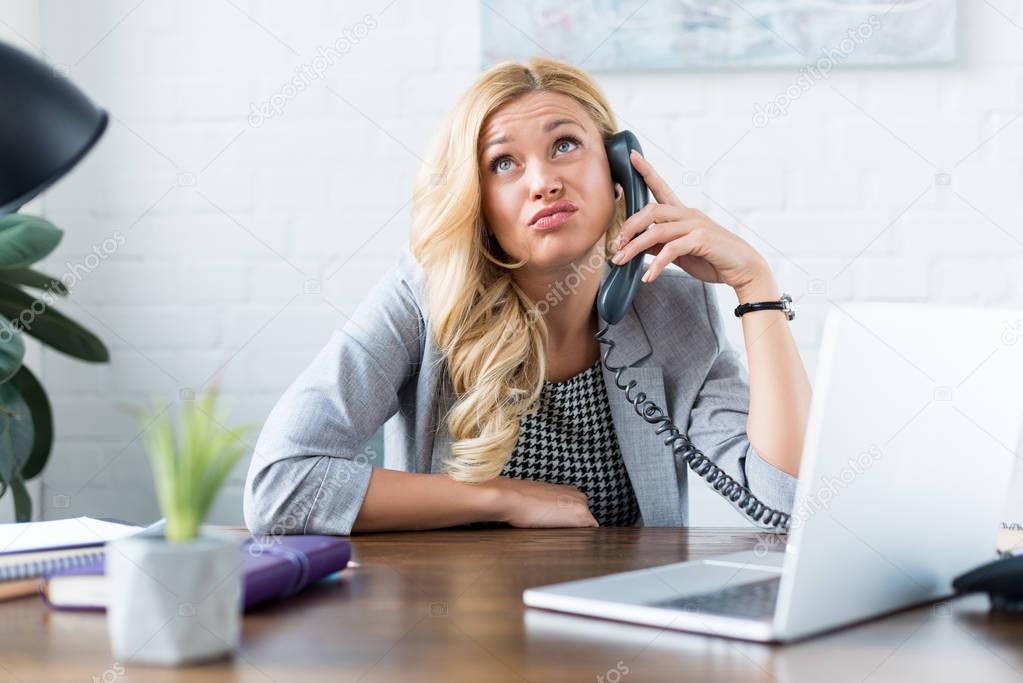 irritated businesswoman talking by telephone in office