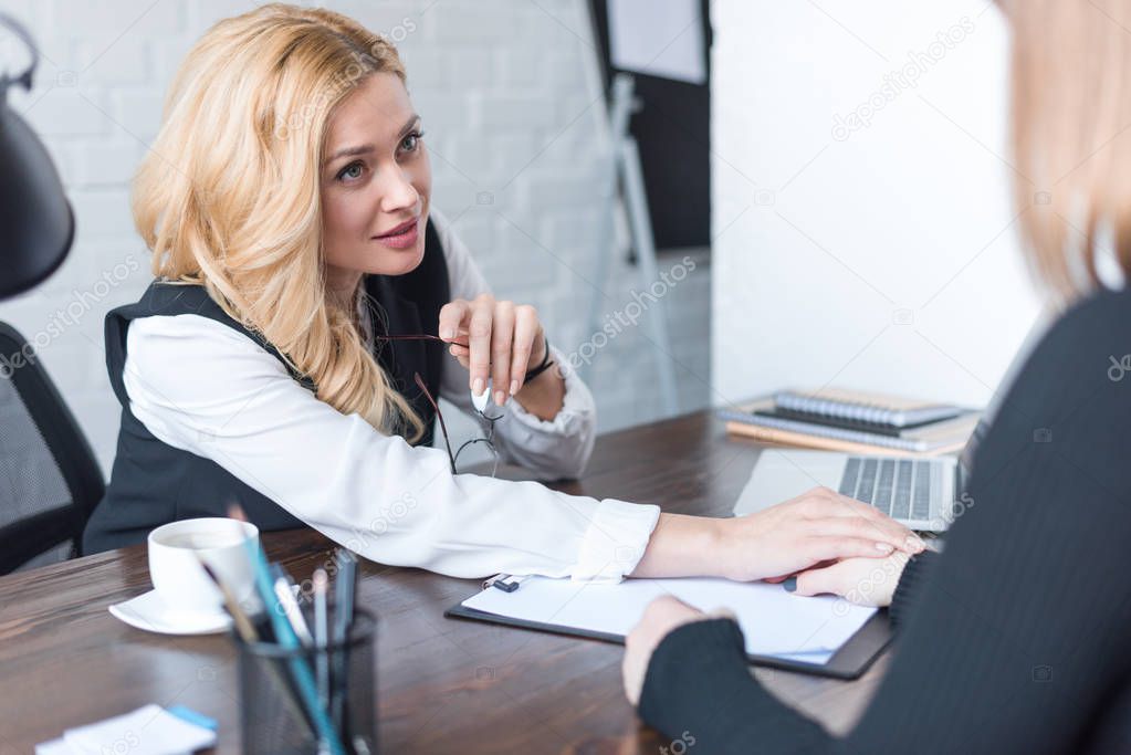 smiling businesswoman palming coworker hand in office