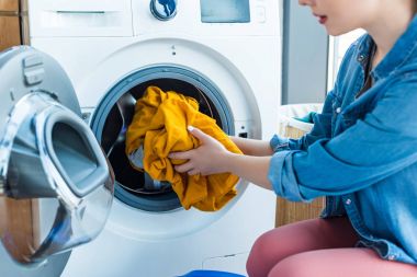 genç kadının Çamaşırhane çamaşır makinesi koyarak atış kırpılmış