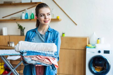 güzel genç kadın holding Çamaşırhane gülümseyen ve uzağa arıyorsunuz