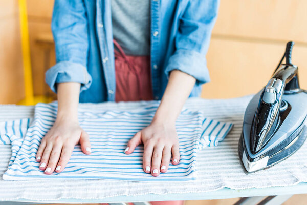 обрезанный снимок молодой женщины гладильной одежды дома
 