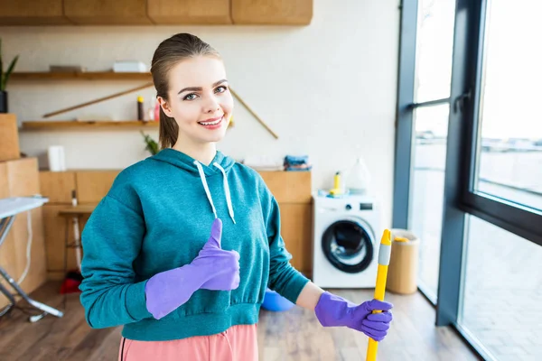 Sorrindo Jovem Mulher Limpeza Casa Com Esfregona Mostrando Polegar Para — Fotografia de Stock