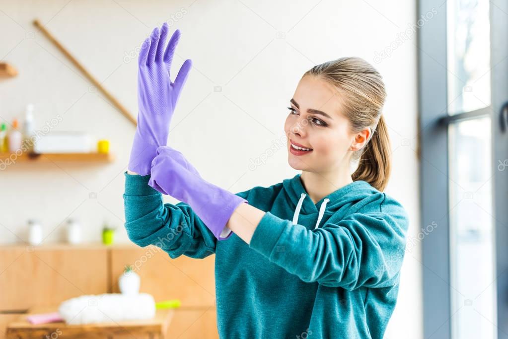 beautiful smiling young woman wearing rubber gloves while cleaning house 