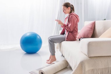 kız evde kanepede oturan ve smartphone kullanarak yan görünüm