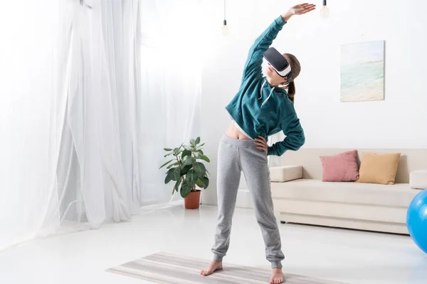 Meisje Permanent Rekken Met Virtual Reality Headset Yoga Mat Thuis — Gratis stockfoto