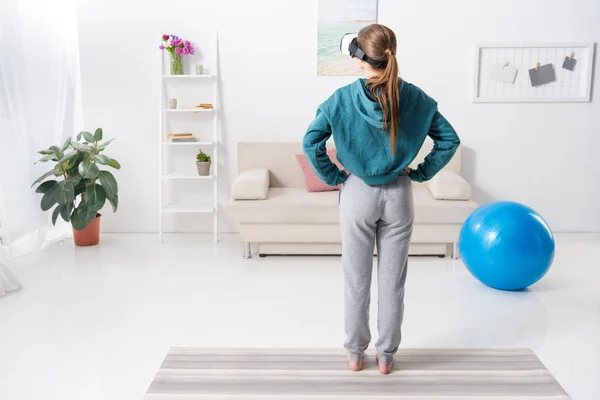 在家里用虚拟现实耳机锻炼女孩的后视 — 图库照片