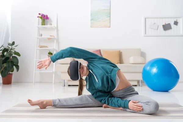 Mädchen Dehnt Körper Mit Virtual Reality Headset Auf Yogamatte Hause — kostenloses Stockfoto