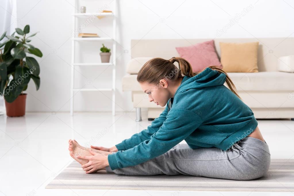 side view of girl stretching in sportswear at home
