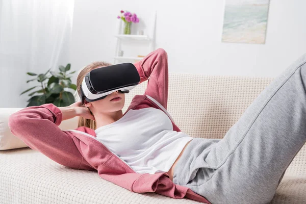 自宅のソファの上の仮想現実のヘッドセット座っている女の子 — ストック写真