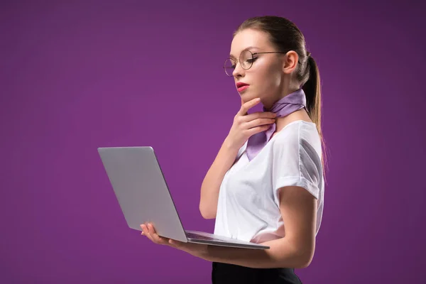 看着在紫色的笔记本电脑孤立的沉思女孩的侧面视图 — 图库照片