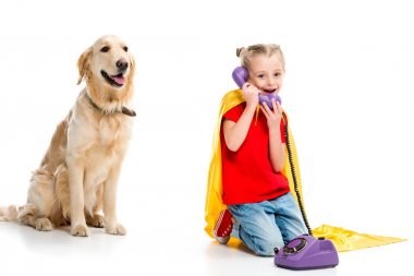 Evet ve üzerinde beyaz izole sarı pelerin giyiyor gülümseyen küçük süper kız ile bej köpek