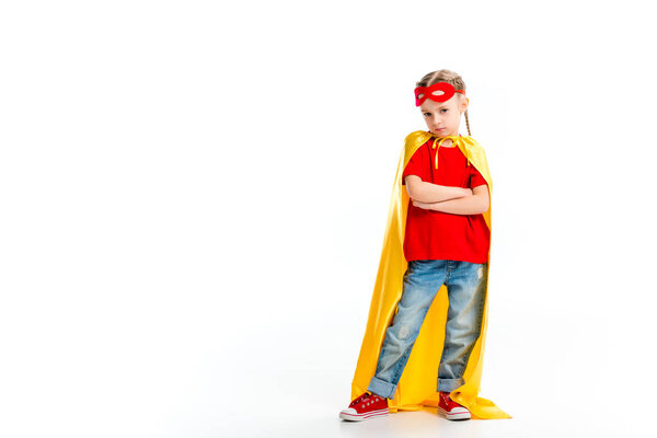 Grumpy little supergirl wearing yellow cape with red mask for eyes on forehead isolated on white