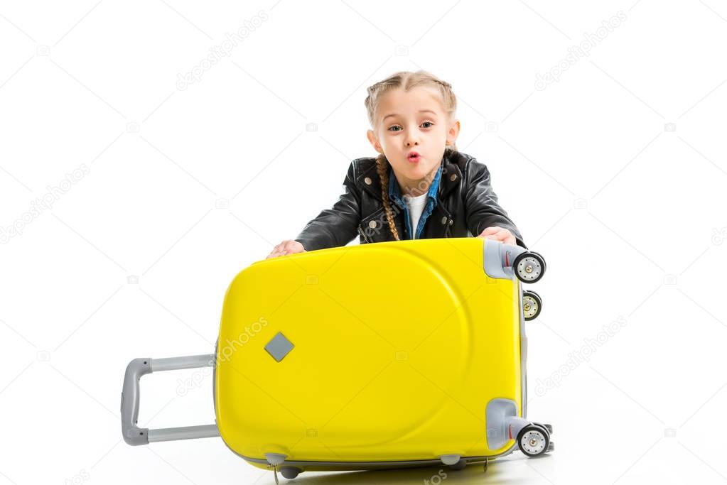 Excited little tourist holding yellow wheel suitcase isolated on white