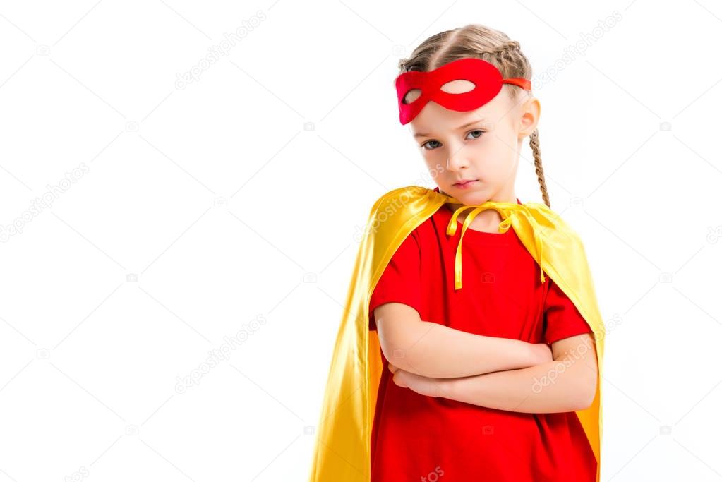 Grumpy little supergirl wearing yellow cape with red mask for eyes on forehead isolated on white