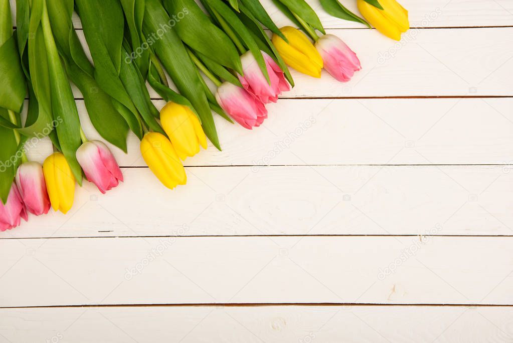 top view of beautiful pink and yellow blooming tulips on wooden surface