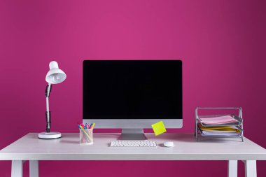 desktop computer with blank screen, office supplies and lamp on table on pink clipart