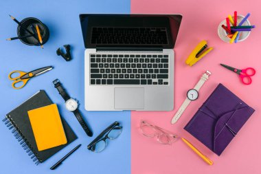 top view of laptop with blank screen, eyeglasses, wristwatches and notebooks divided at male and female workplace clipart