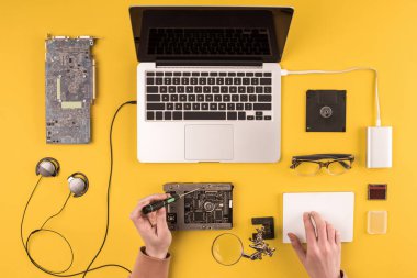 cropped shot of person fixing laptop on yellow  clipart