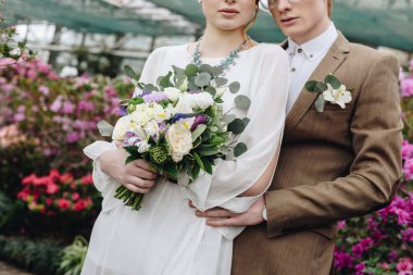şık genç damat ve gelin düğün buket ayakta birlikte Botanik Bahçesi ile kırpılmış