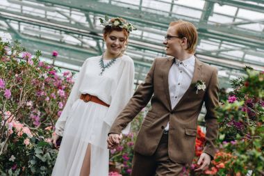Elele ve Botanik bahçesinde çiçekler arasında yürüyüş mutlu genç redhead Düğün çifti