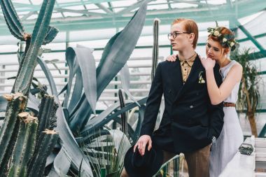 beautiful young redhead wedding couple standing together in botanical garden clipart