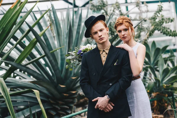 植物園でカメラを見てスタイリッシュな若い赤髪結婚式のカップル — ストック写真
