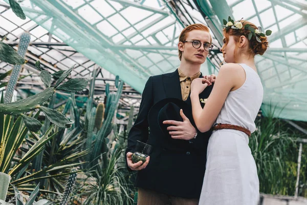 美丽的年轻红发夫妇与订婚戒指在珠宝盒站在一起在植物园 — 图库照片