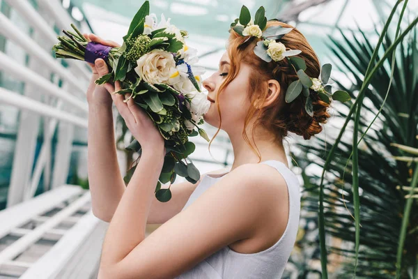 美丽的年轻新娘在花花圈举行婚礼花束的侧面视图 — 图库照片