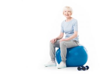 Üst düzey sporcumuz Fitness topu üzerinde zemin üzerinde beyaz izole dumbbells ile oturan