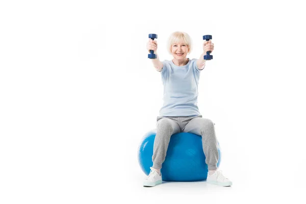 Smiling Senior Sportswoman Holding Dumbbells While Sitting Fitness Ball Isolated — Stock Photo, Image