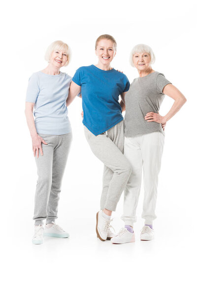 Three smiling sportswomen standing isolated on white