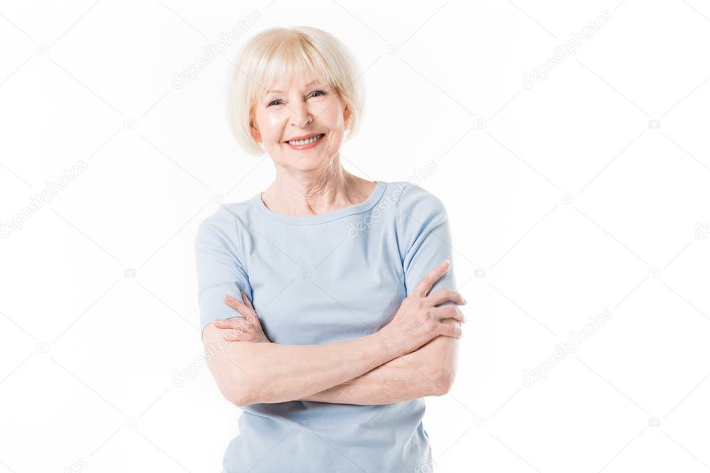 Smiling senior woman standing with crossed arms isolated on white