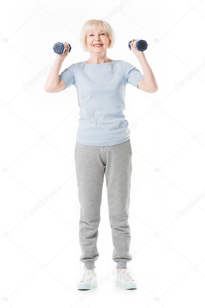 Happy senior sportswoman holding dumbbells in hands isolated on white